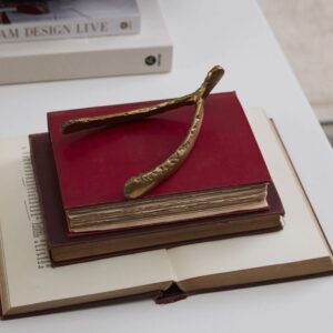 A gold twig bookmark on two stacked books with a red cover.