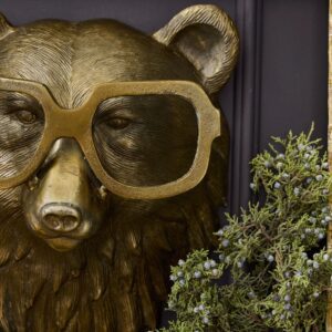 A bear statue wearing glasses and holding onto some bushes