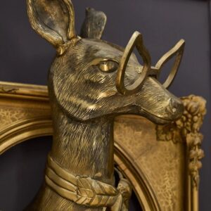 A gold deer head mounted to the side of a wall.