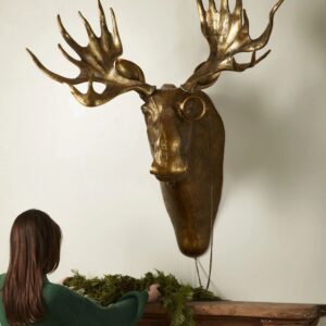 A woman looking at a large metal moose head.