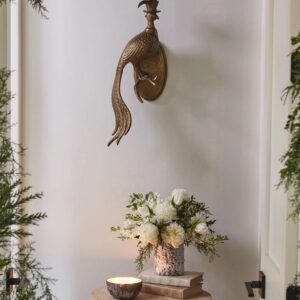 A wall mounted bird statue with flowers in it.