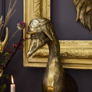 A gold goose statue sitting next to a candle.