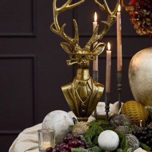 A table with candles and a gold deer head.