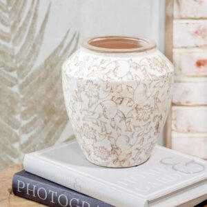 Elegant white ceramic vase with intricate floral patterns on a stack of books.