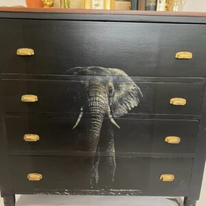 A black dresser with an elephant painted on it