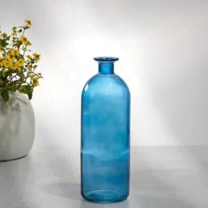 Tall blue glass bottle with a narrow neck on a white surface.