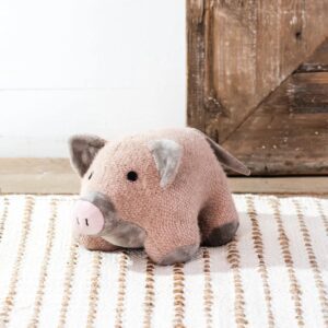 A cute plush pig toy sitting on a striped rug.
