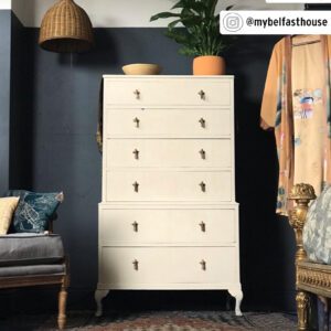 Vintage cream dresser with unique keyhole handles in a stylish room.