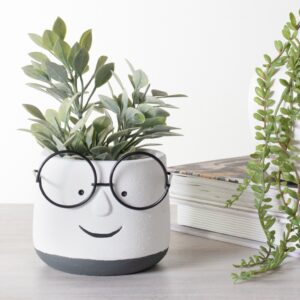 A smiling planter with glasses holding a green plant.