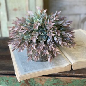 A decorative purple plant in a rustic pot on an open book.