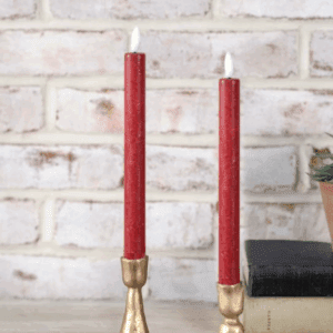 Two red candles on golden holders, one lit and the other unlit.